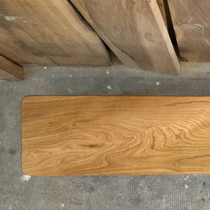 Extrémité gauche de l'assise vue du dessus, angles arrondis, devant des planches de noyer brut