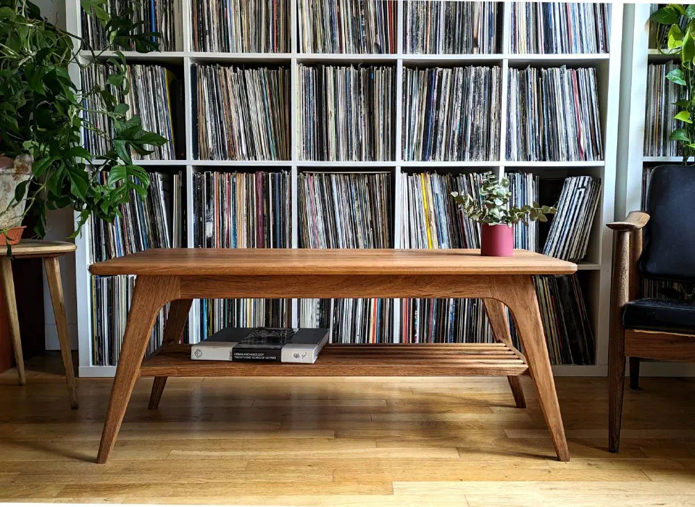 Table basse en noyer massif devant une bibliothèque de vinyles, un livre posé sur la tablette à claire-voie