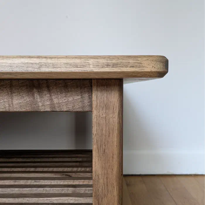 Angle de la table en noyer : chant du plateau adouci, ceinture et pied droit