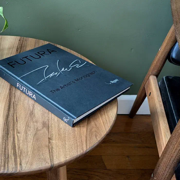 Plateau rond en noyer vu de près avec un livre posé dessus, à côté du fauteuil